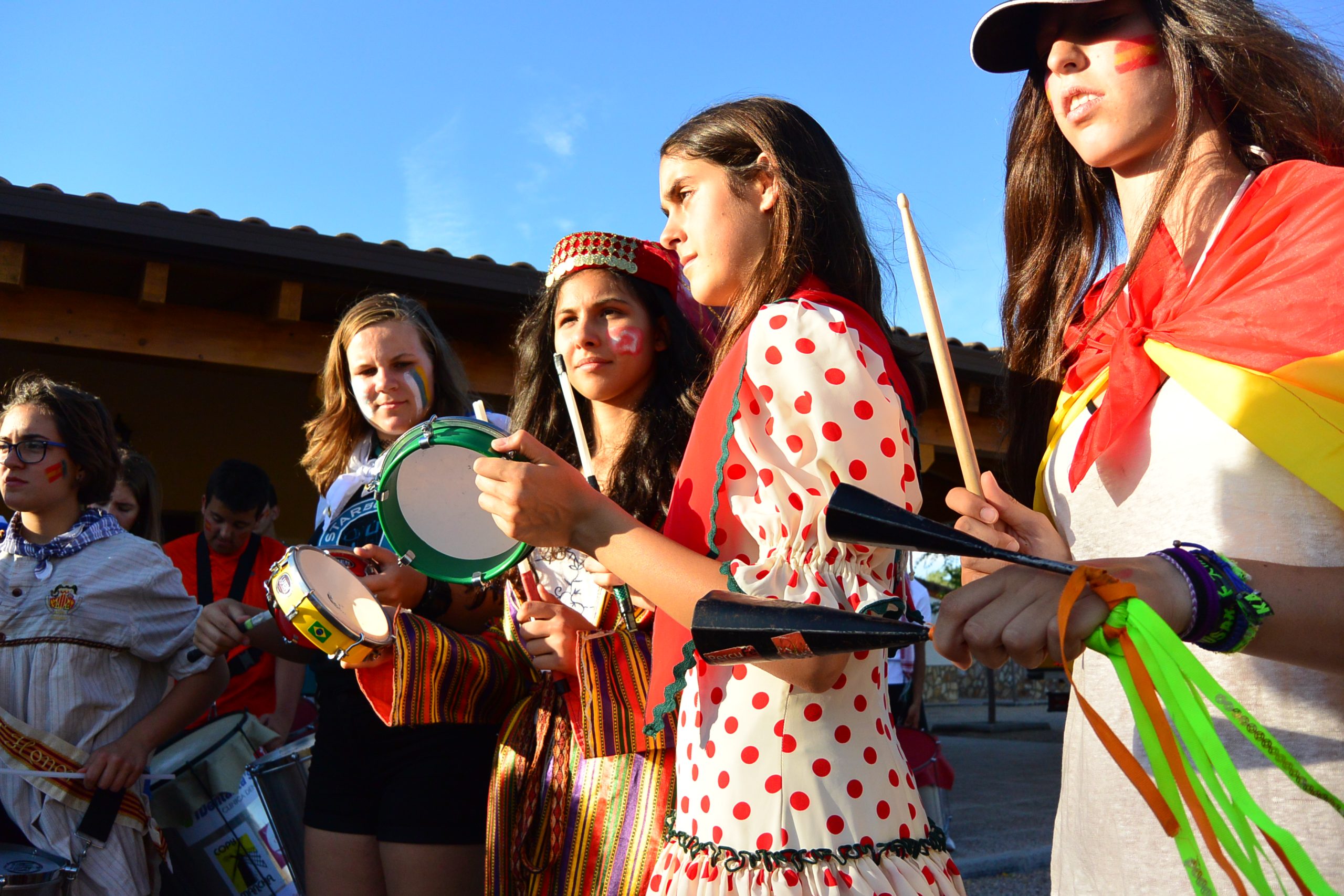 Three women in various national dress banging instruments.