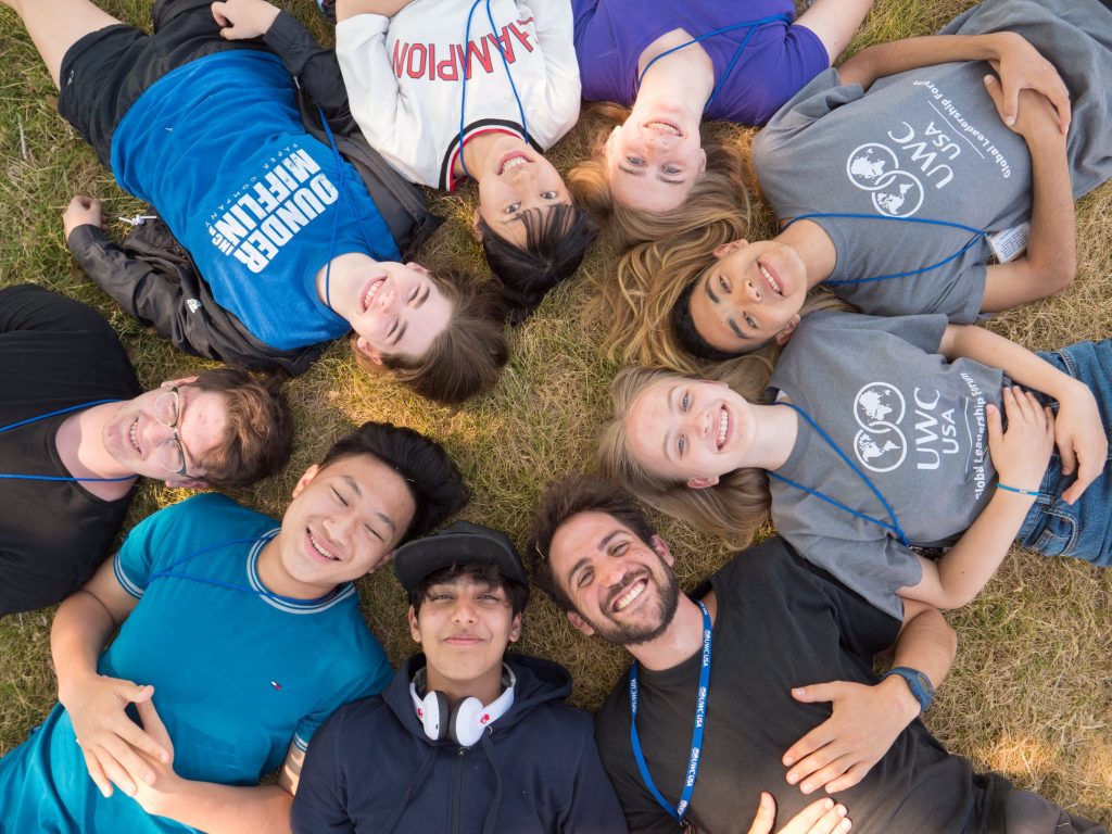 A group of student laying on the ground in a ring shape with the heads in the middle