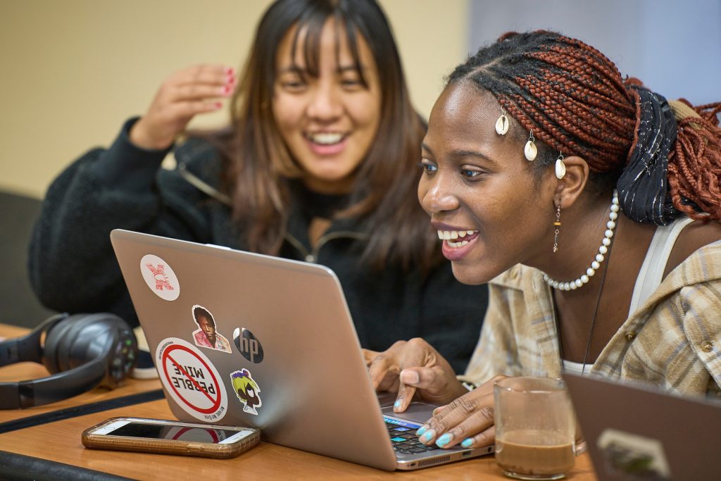 Two students working happily together on a laptop