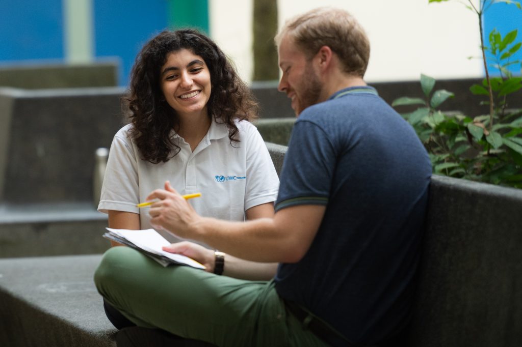 A male teacher talks to a female student who is smiling