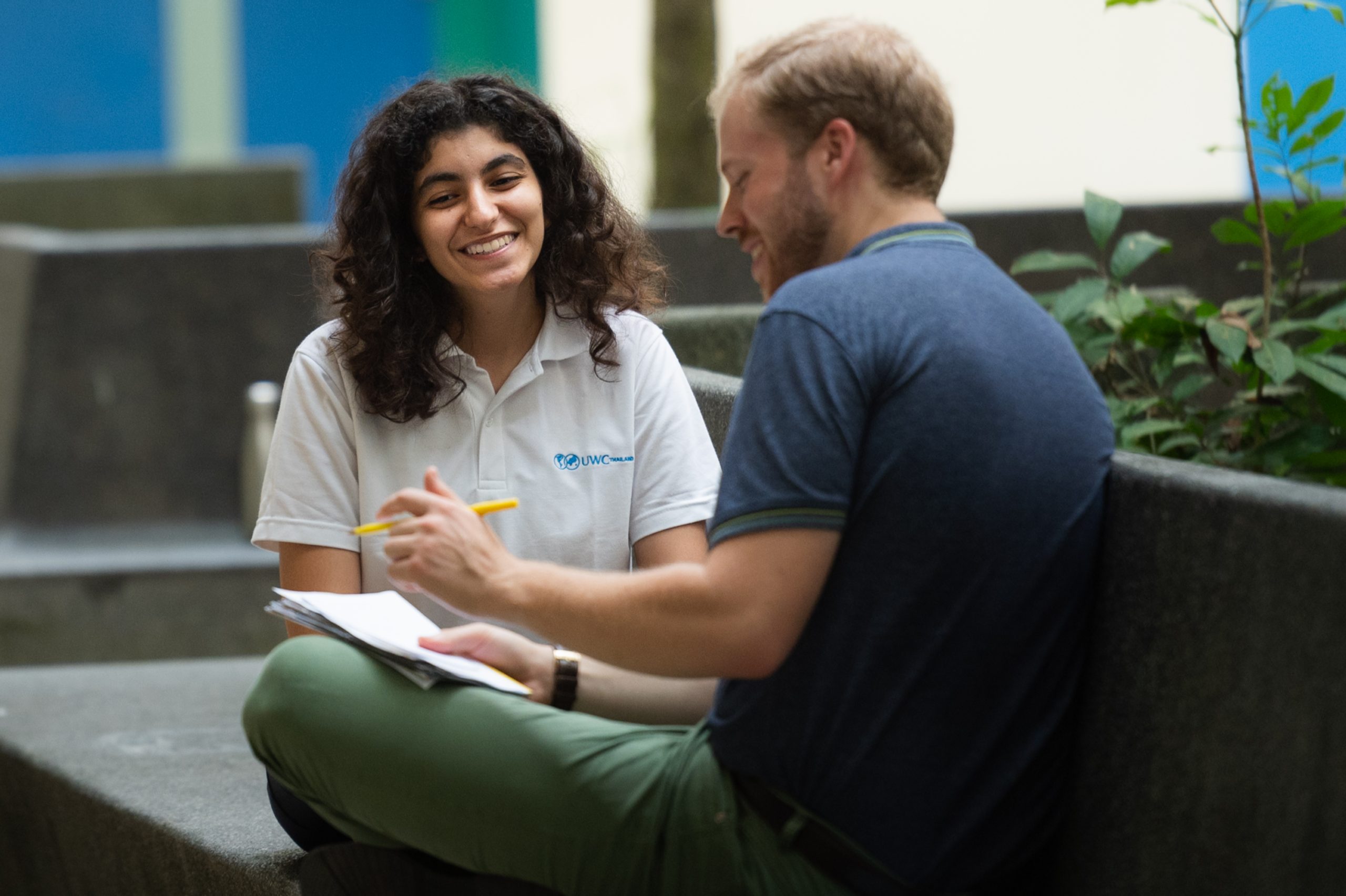 A male teacher talks to a female student who is smiling